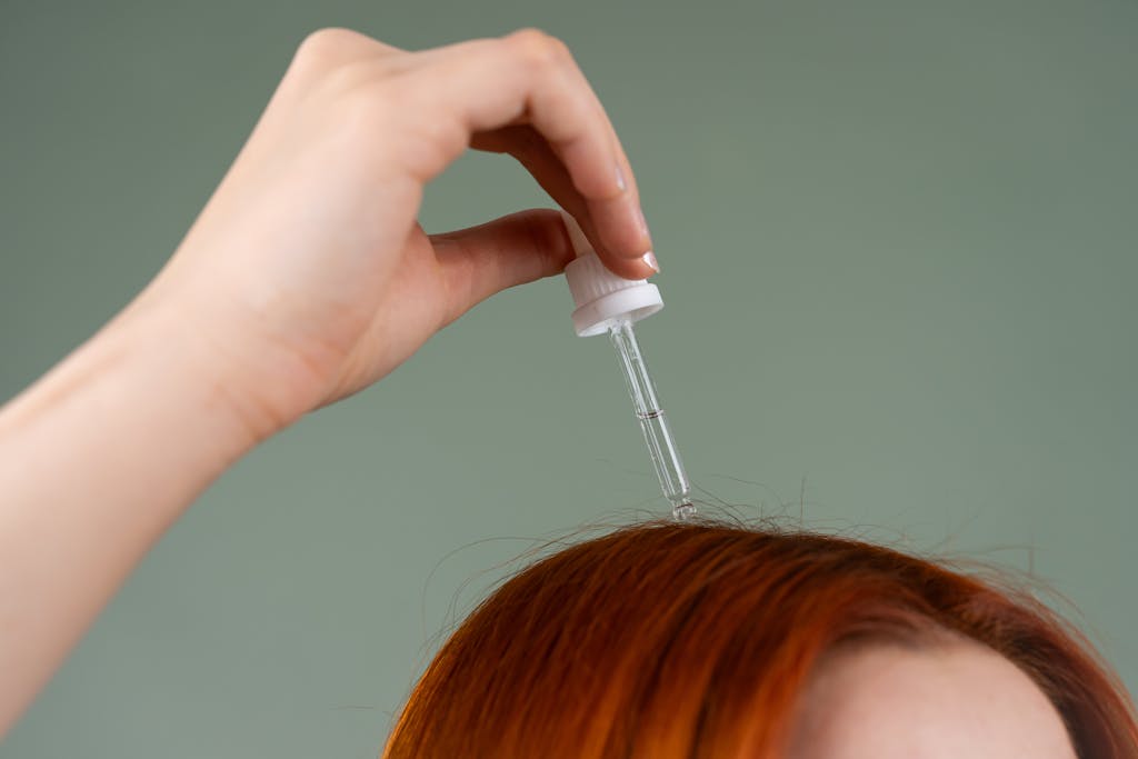 Schuppen einfach wegessen? Studien zeigen, was wirklich gegen den Juckreiz hilft 4 Close-up of hand applying hair serum on red hair with a dropper.