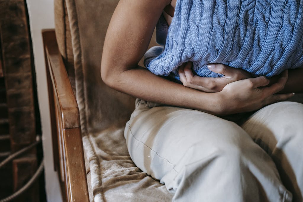Scheinfasten bei Morbus Crohn: Therapie hilft 69 Prozent 1 Crop unrecognizable female touching belly while having acute pain in stomach sitting on couch